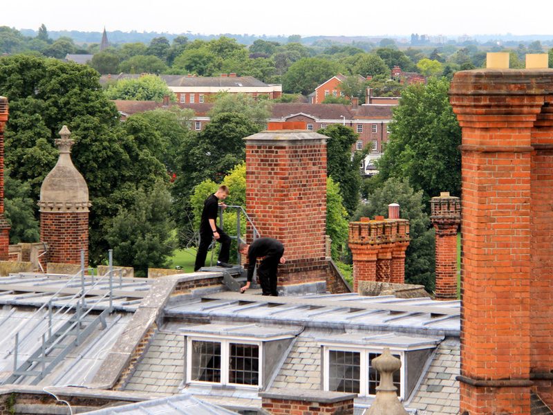 Roofers working on a roof with rooftops beyond